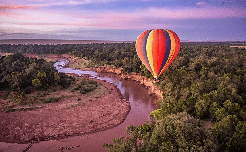 Hot air balloon floating over the Masai Mara savannah at sunrise during a Masai Mara safari tour