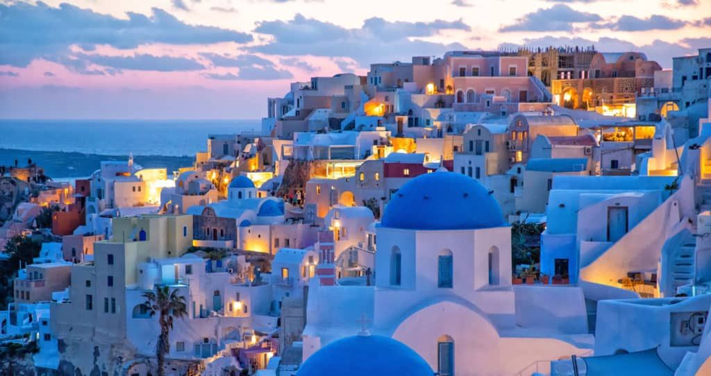 Greece tour Santorini — iconic blue-domed churches at sunset over Aegean Sea, Armani Tours Greece cultural holiday