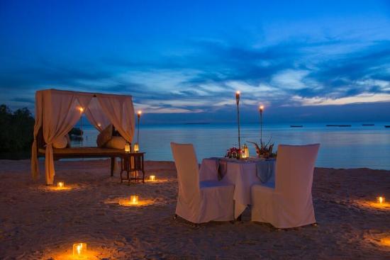 Romantic Beach Dinner — Private candlelit dining on the beach with ocean waves and sunset views at luxury honeymoon resort